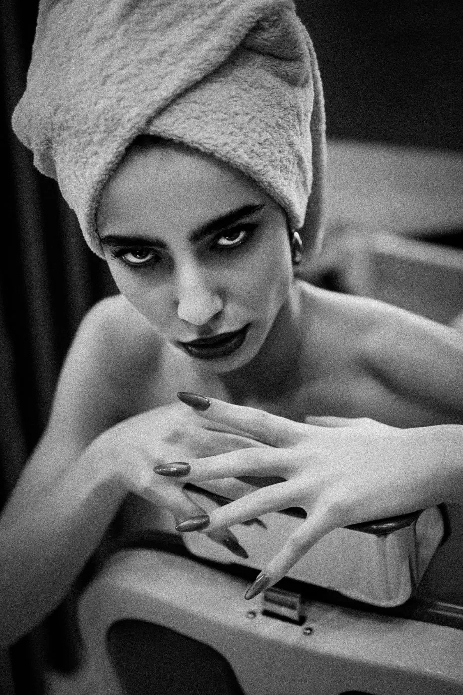 A towel turban; long painted nails resting on the chair.