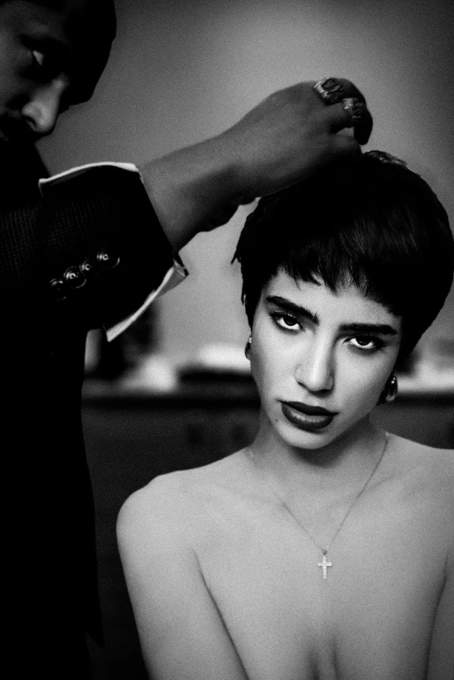 The hairdresser's hand at the crown of her head, fixing the bangs into shape.